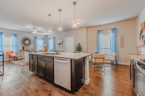 a kitchen with an island and a living room with a table and chairs